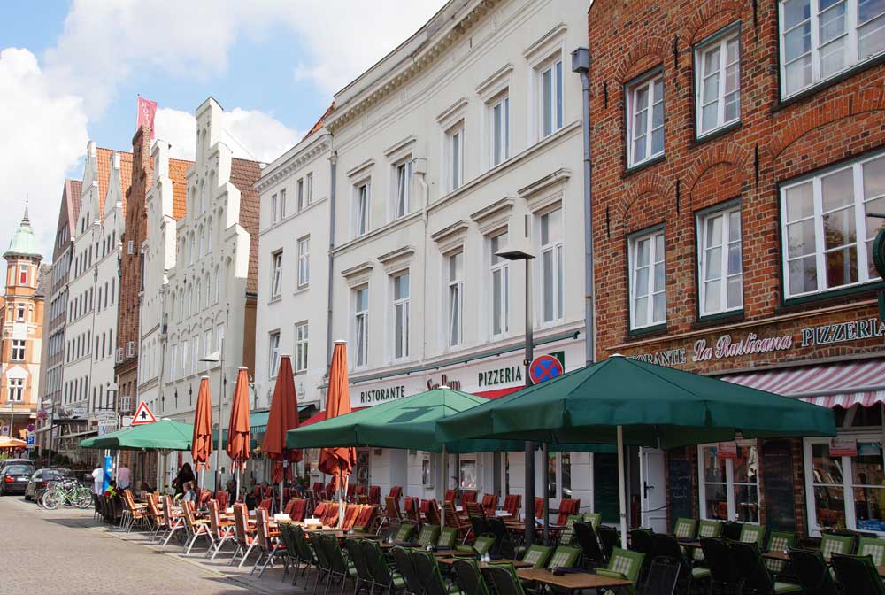 Von der Obertrave in Lübeck schauen Sie auf die Sehenswürdigkeiten Holstentor und Salzspeicher Obertrave mit Restaurants